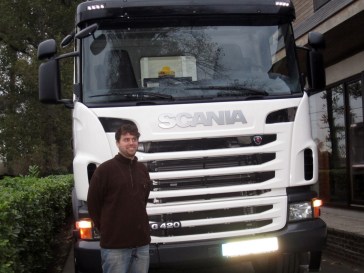 Claude Vandenbroucke, zaakvoerder, voor de cabine van zijn SCANIA-vrachtwagen