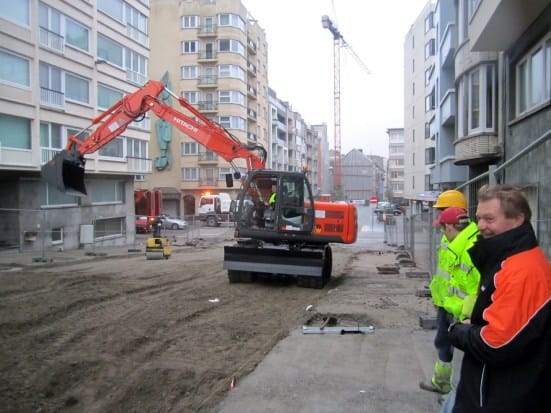 Realisatiefoto van grondwerken met een Claude-kraan in actie op een werf