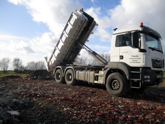 Witte MAN kiepvrachtwagen met opschrift Claude die een lading puin lost